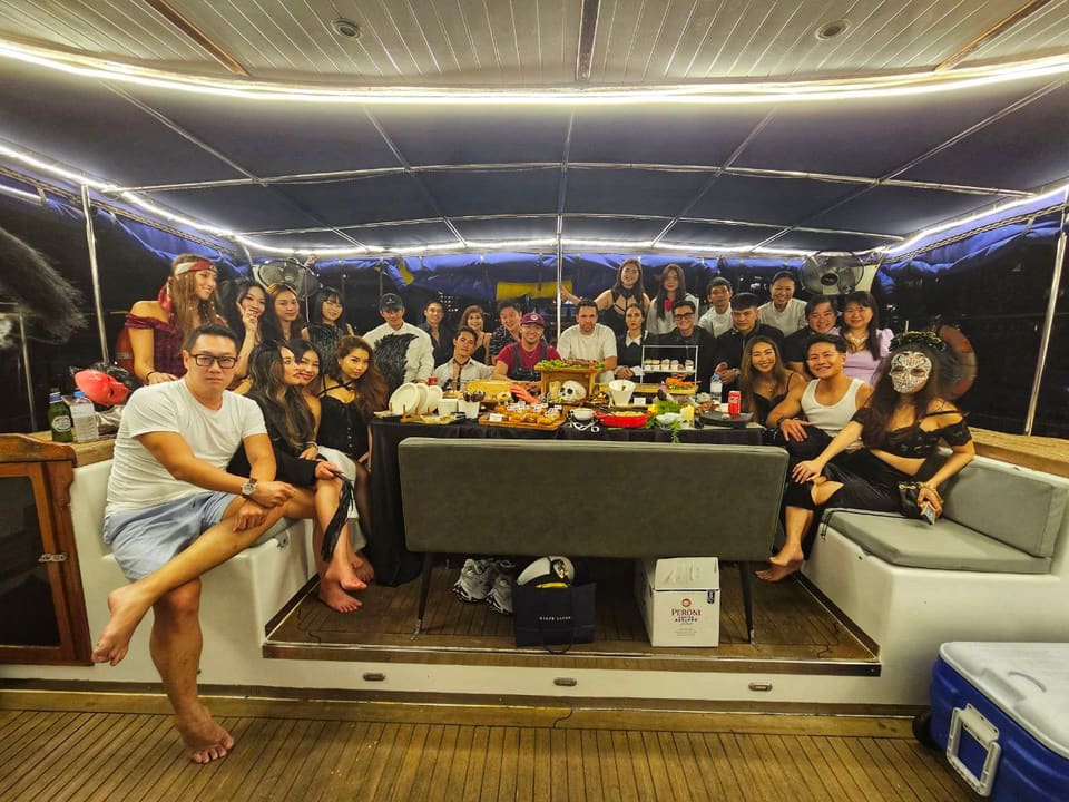 A costume party of nearly thirty on the lit aft deck at night
