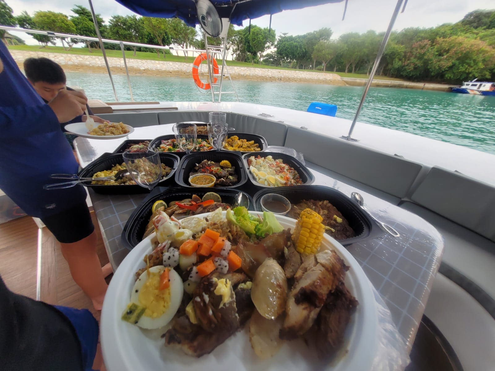 Mini-buffet trays laid out along the aft deck bench at anchor