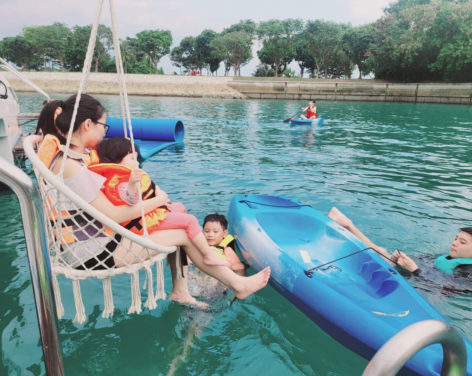 The hanging chair over the stern, with children in child-size life jackets in the water below