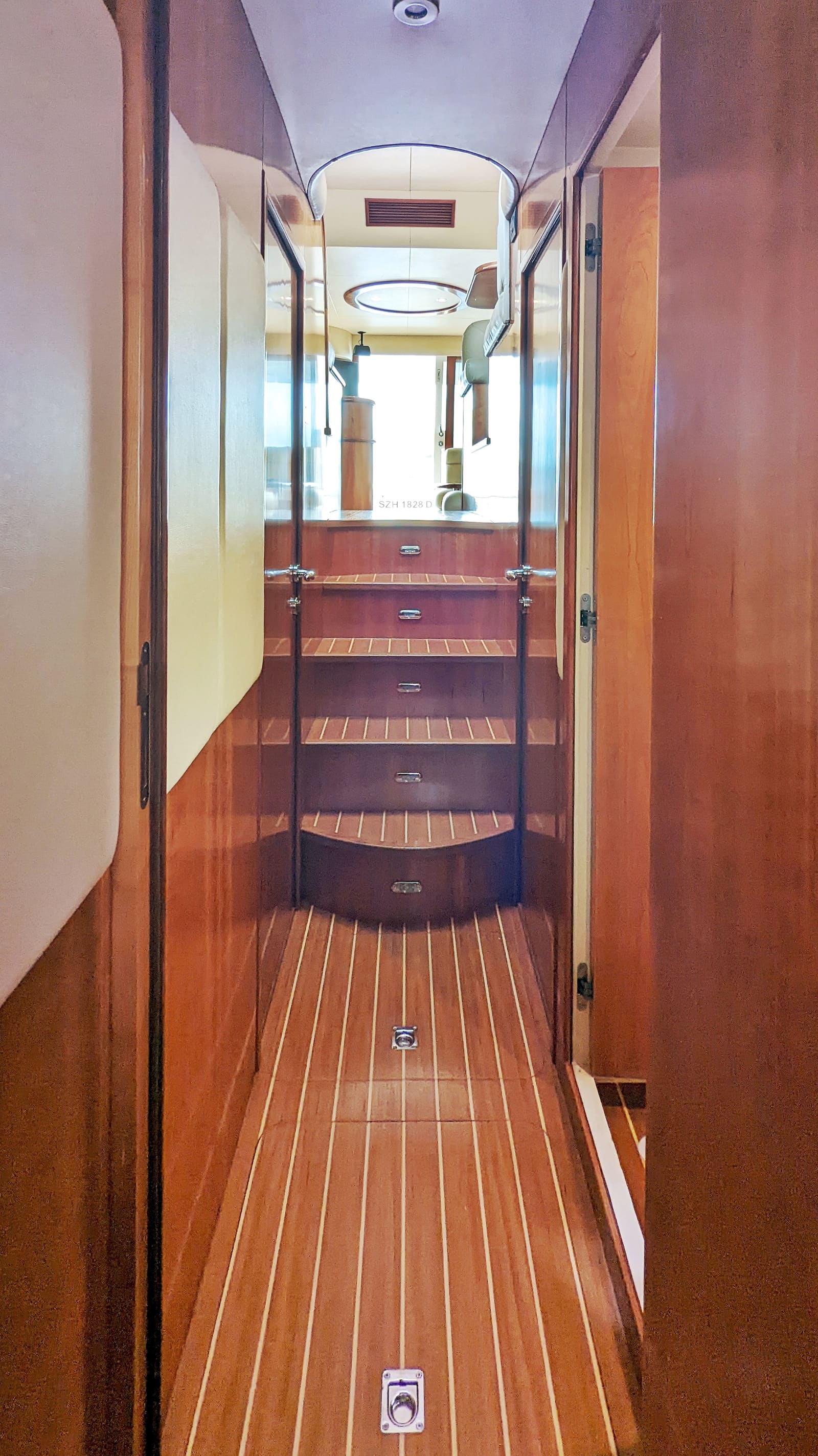 Teak companionway down from the saloon, with drawers built into the steps and the cabin doors either side