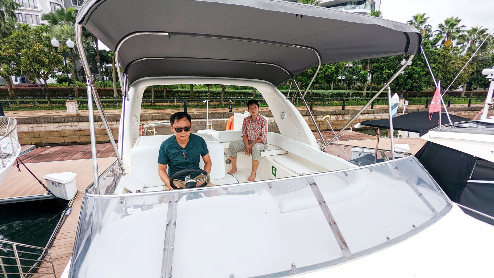 The flybridge and its bimini seen from the bow at the berth, with the skipper at the upper helm