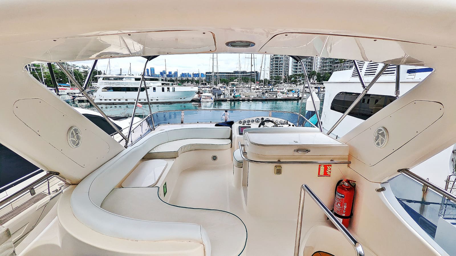 Flybridge alongside at ONE°15 Marina, with wraparound seating under the bimini and the upper helm looking out over the pontoons