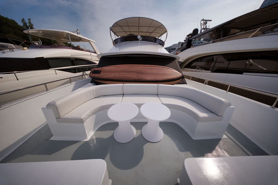 Curved lounge seating and cocktail tables on the foredeck, the paddleboard stowed behind