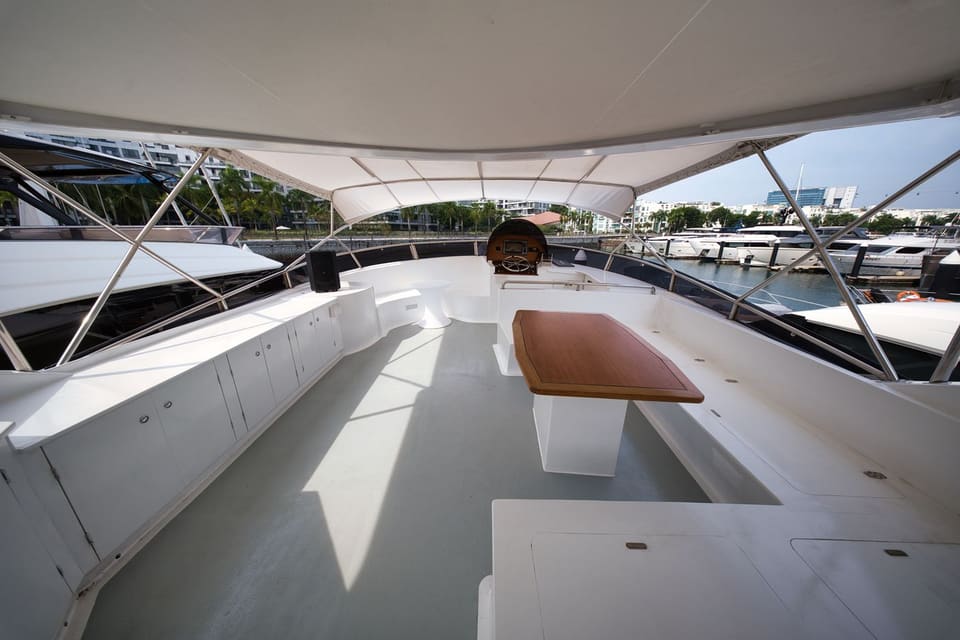 Bimini-shaded flybridge with the dining table, bench seating and upper helm